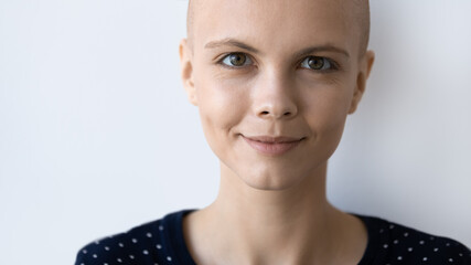 Head shot close up cropped image of smiling woman with bald after chemotherapy head, isolated on...