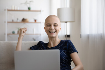 Overjoyed young hairless after chemotherapy woman making yes gesture, celebrating getting email...
