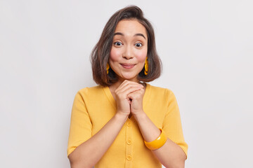 Portrait of good looking young Asian woman with natural dak hair healthy skin keeps hands together...