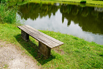 Fototapeta na wymiar wood bench empty aside lake coast calm water in france