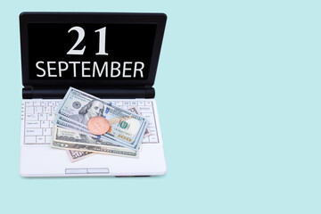Naklejka na ściany i meble Laptop with the date of 21 september and cryptocurrency Bitcoin, dollars on a blue background. Buy or sell cryptocurrency. Stock market concept.