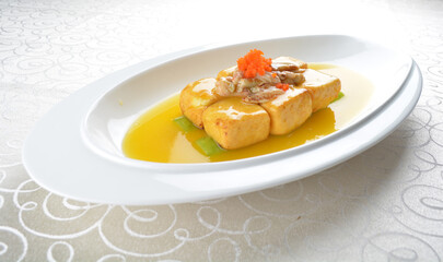 braised handmade bean curd tofu with crabmeat, luffa plant, roe in golden yellow sauce in white background asian halal menu