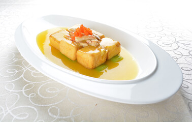braised handmade bean curd tofu with crabmeat, luffa plant, roe in golden yellow sauce in white background asian halal menu