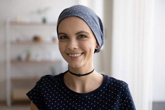 Head shot portrait of smiling sincere millennial caucasian woman wearing scarf on bald head struggling with oncology disease, feeling optimistic about cancer fight, remission or recovery concept.