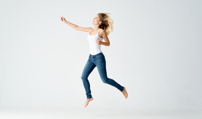 pretty woman in jeans movements dance barefoot light background