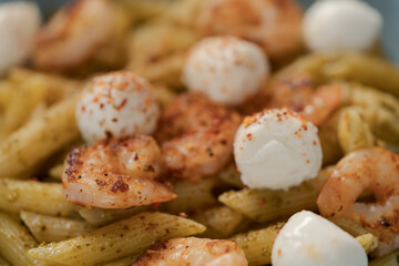 Penne pasta with shrimps and mozzarella and pesto in blue bowl