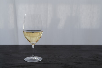 White wine in a wineglass on black oak table with copy space