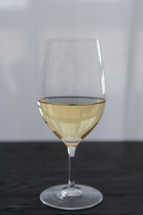 White wine in a wineglass on black oak table with copy space