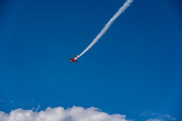 the red plane makes difficult turns and blows white smoke against the blue sky at the Max-21 aerospace salon in Zhukovsky on July 24, 2021