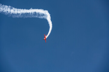the red plane makes difficult turns and blows white smoke against the blue sky at the Max-21 aerospace salon in Zhukovsky on July 24, 2021