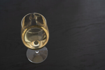 Fototapeta na wymiar White wine in a wineglass on black oak table with copy space
