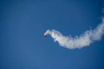the red plane makes difficult turns and blows white smoke against the blue sky at the Max-21 aerospace salon in Zhukovsky on July 24, 2021