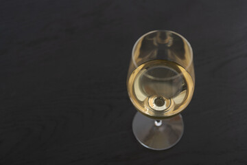 White wine in a wineglass on black oak table with copy space