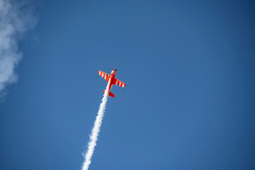the red plane makes difficult turns and blows white smoke against the blue sky at the Max-21 aerospace salon in Zhukovsky on July 24, 2021