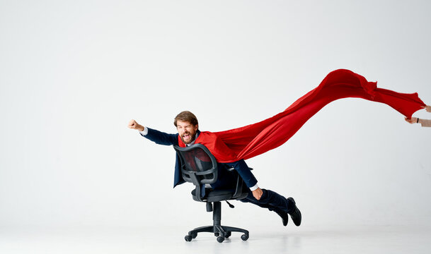 a man with a red raincoat rolls around in an office chair manager superman