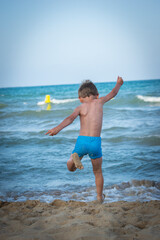 Niño jugando y saltando en la playa