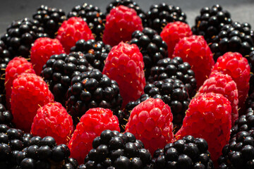 Summer berries. Ripe raspberries and blackberries. Healthy eating. Healthy foods. Juicy berries for dessert. Background for cafe and restaurant. Delicious still life. Seasonal products. Red and black.