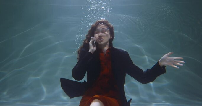 Cinematic under water portrait of happy young mixed race business woman in office suit talking on phone slow motion.