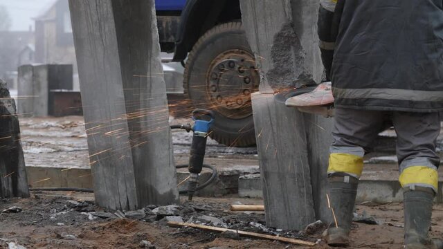 Worker or builder cutting concrete piles with cutter, cropper or circular saw on building site. Concept of deep foundation removal, piling cropping or trimming, operation of construction work process.