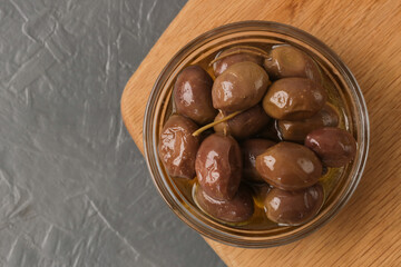 Olives and olive oil in bowl on woden table