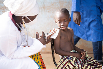 Black vaccinator immunizing a small frightful African toddler against Covid in a rural vaccination...