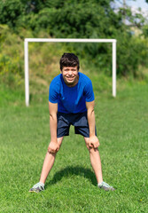 teenage boy exercising outdoors, sports ground in the yard, standing as a goalkeeper at the soccer gate, healthy lifestyle