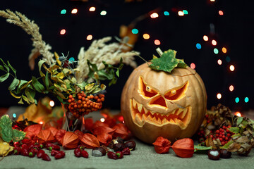 Halloween Still life with Jack-o-Lantern pumpkin and autumn leaves. Focus on the foreground. Autumn festive still life. 

