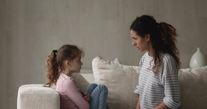 Irritated by bad naughty behavior angry young latin mother or nanny lecturing scolding stressed unhappy small kid girl, different generations gap, family relationship problems, crisis conflict.