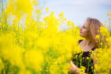 Blonde girl with luxurious long hair in a blooming rapeseed field of Ukraine