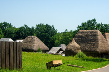 Fototapeta na wymiar Rural scene with thatch roof buildings, hay stack and wheelbarrow, near Sibiu, Romania