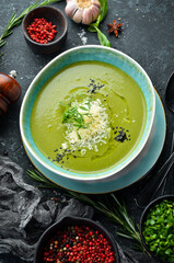 Healthy food. Green soup with broccoli and spinach in a plate on a black stone background. Top view. Rustic style.