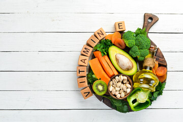 Foods rich in vitamin E: pumpkin, broccoli, dried apricots, parsley, avocado and vegetables. The inscription "Vitamin E". Top view.