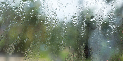 Rain drops on glass window. Raindrops falling from glass material. Abstract nature background. Copy space for text. Focus on foreground.