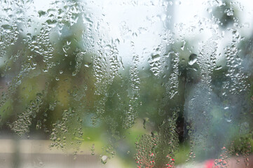 Rain drops on glass window. Raindrops falling from glass material. Abstract nature background. Copy space for text. Focus on foreground.