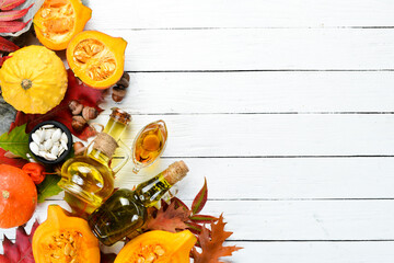 Pumpkin oil and pumpkins. Autumn vegetables. flat lay. On a white wooden background. Top view. Free...