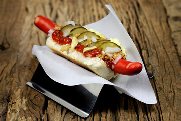 Danish style hot dog with traditional red sausage on rustic wooden background