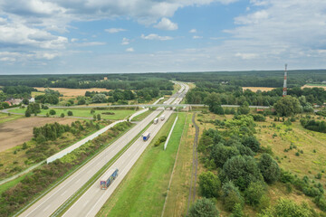 Betonowa autostrada przebiegająca przez las. Zdjęcie wykonane z wysokości przy użyciu drona. - obrazy, fototapety, plakaty