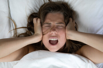 Young depressed unhappy woman lying in bed with health problems,...