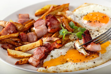Eating french fries with fried eggs and bacon