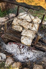 Meat Grilled in Foil on Flaming BBQ Grill. Barbecue cooking flaming grill grid Food Background in aluminum foil. Portrait of the cooking food with aluminum foil packing