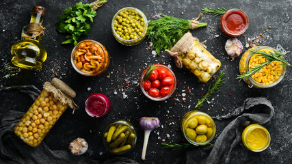 Food stocks in glass jars. Pickled vegetables. On a black background. Top view.