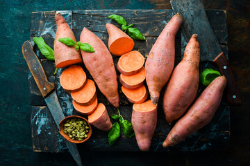 Raw organic sweet potatoes on a wooden background. Dietary food. Top view.