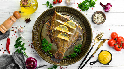 Baked flounder fish with lemon and spices on a metal baking dish. Seafood. Top view. Free space for text.