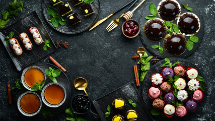 Set of sweets and desserts for coffee and tea on a black stone background. Top view. Rustic style.