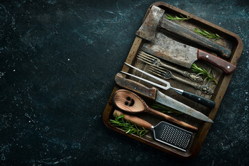 Old kitchen utensils on a metal kitchen tray on a black stone background. Retro tableware. Free space for text.