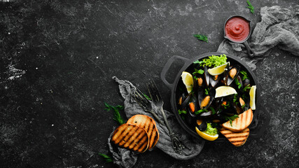 Boiled mussels with garlic, parsley and lemon in a frying pan. Top view. Free space for your text.
