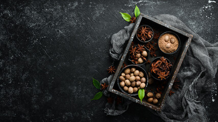 Set of fragrant Indian spices on black stone background. Nutmeg and Anise in bowls. Top view. Free space for your text.