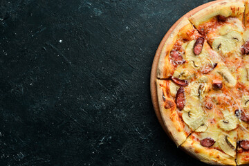 Homemade Pizza with sausages, mushrooms and cheese. On a black stone background. Free space for text.