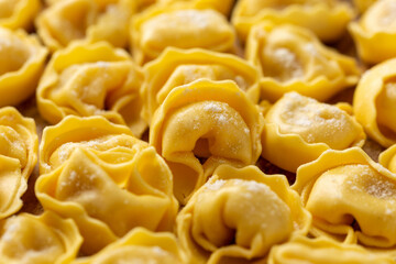 Mini raw Ravioli with flour and basil on wooden board