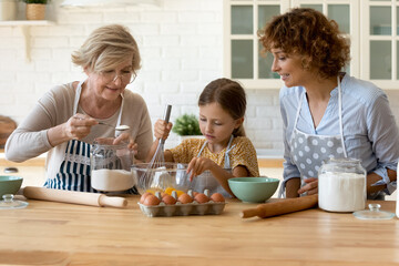 Happy three generations of women baking, cooking dough for cookie or pie in modern kitchen...